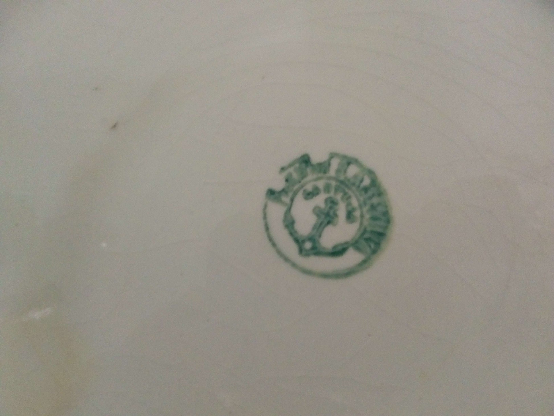 Sello verde de la Cartuja de Sevilla Pickman en la base de una palangana de porcelana antigua, ideal para decoración vintage en el hogar.