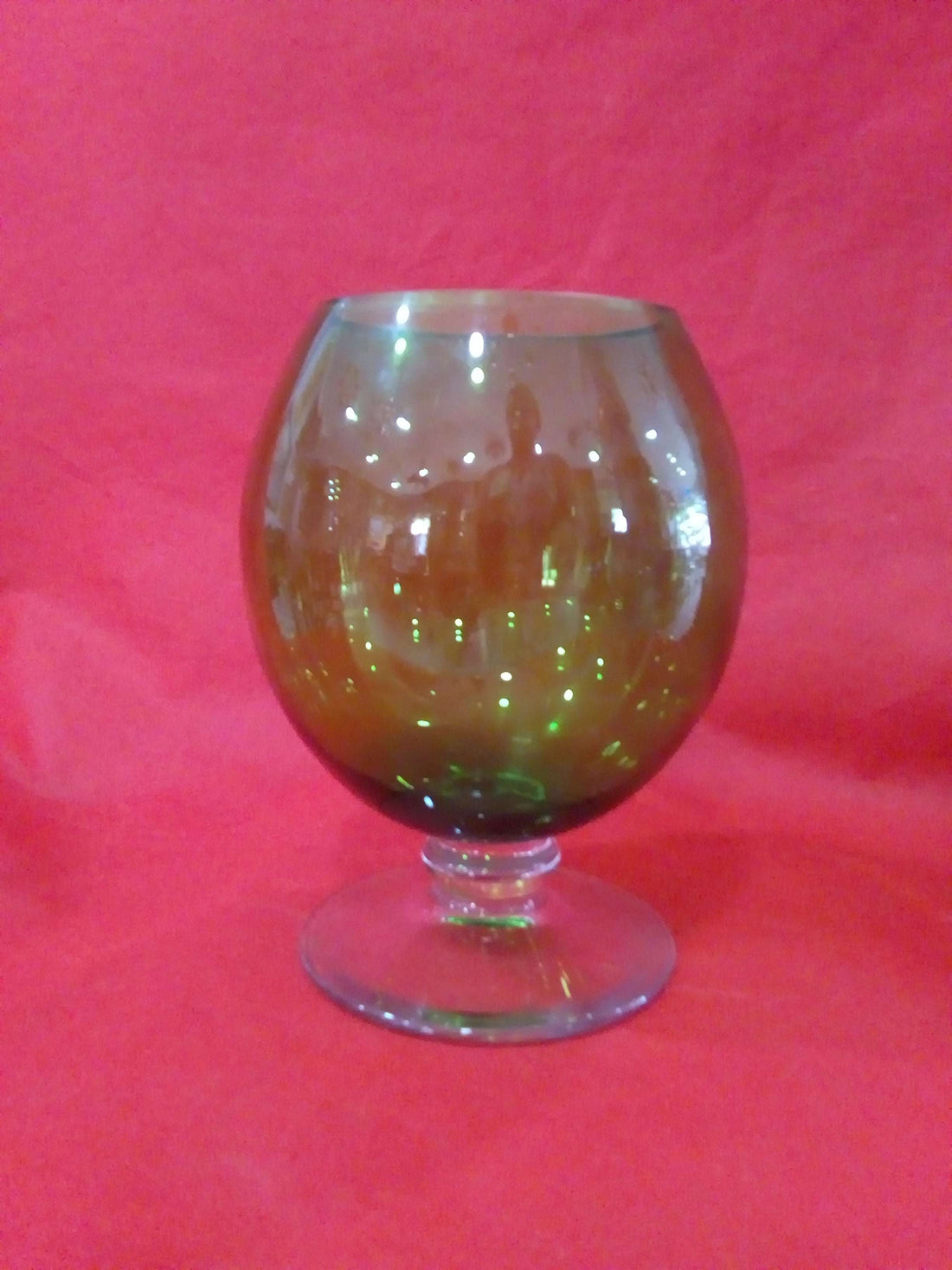 Copa de cristal verde y blanco con diseño elegante y vintage sobre fondo rojo. Ideal para decoración de interiores en estilo clásico.