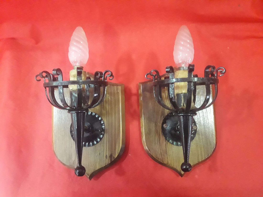 Pareja de apliques antiguos electrificados de gran calidad en hierro forjado y base de madera, ideales para decoración vintage de interiores.