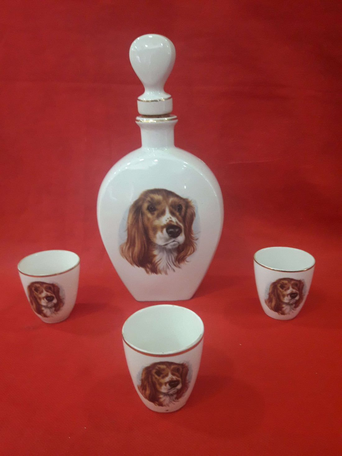 Botella de licor de porcelana con 3 vasitos decorada con imagen de perro, excelente calidad para decoración vintage en hogar o bar.