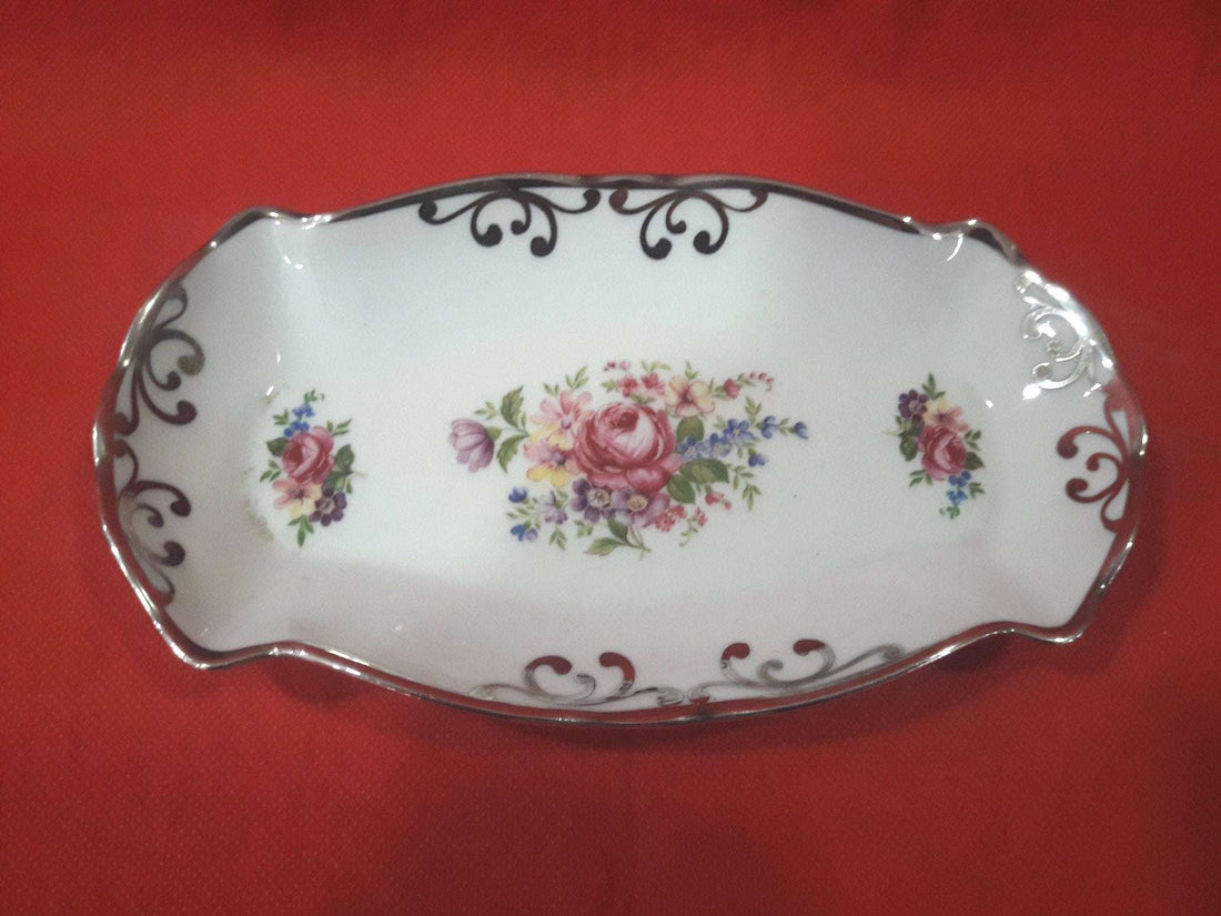 Bandeja de porcelana bohemia decorada con hilo de plata, alta calidad, con diseño floral central y bordes curvos sobre fondo rojo. Ideal para decoración elegante en el hogar.