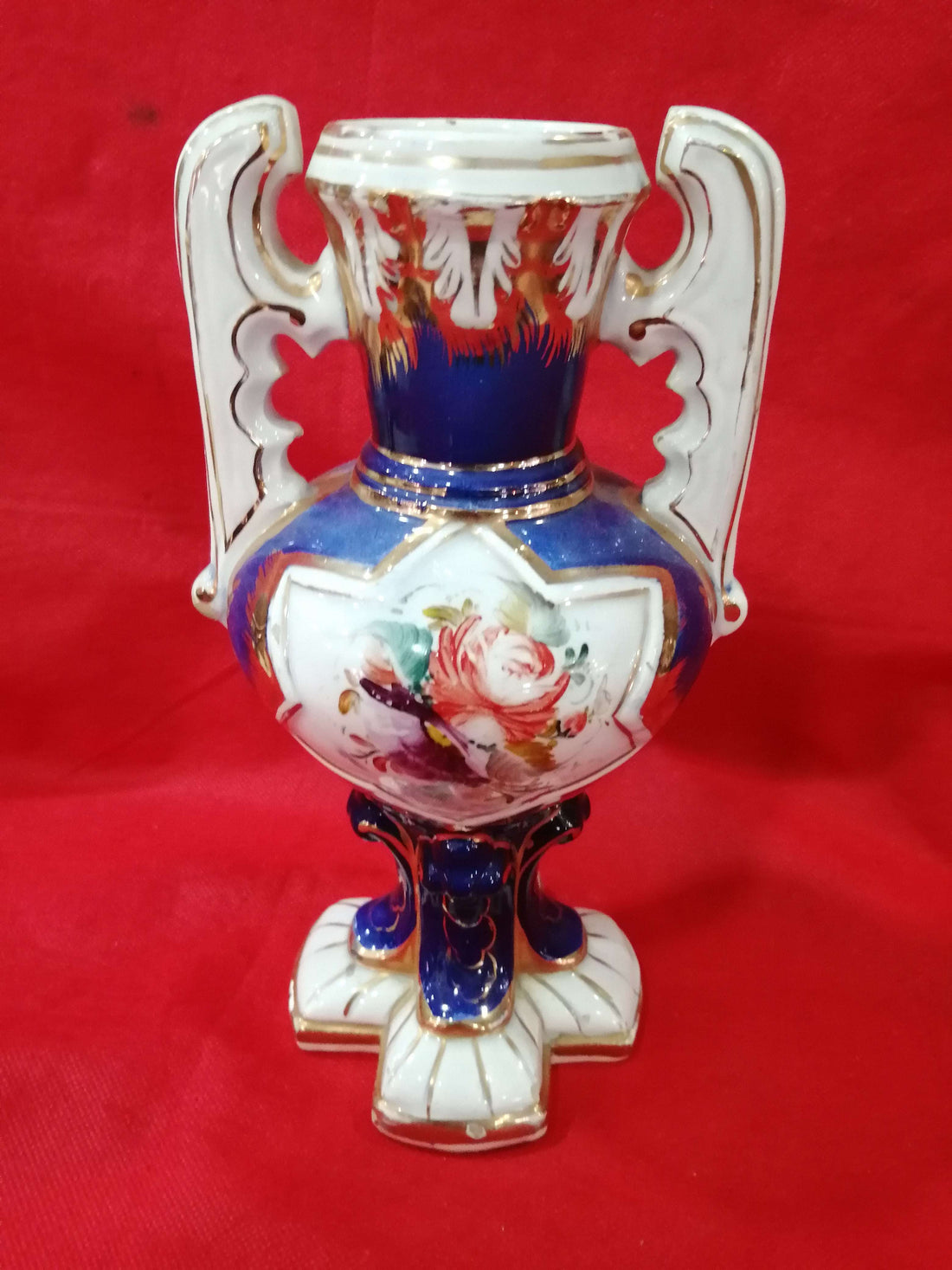 Jarrón de cerámica pintado a mano, diseño exclusivo con flores y detalles dorados sobre fondo azul y blanco. Ideal para decoración elegante y antigua.