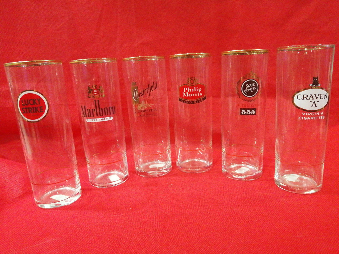 Vasos de tubo con filo dorado y decoración de marcas de cigarrillos como Marlboro y Lucky Strike. Set de 6 piezas para decoración vintage.