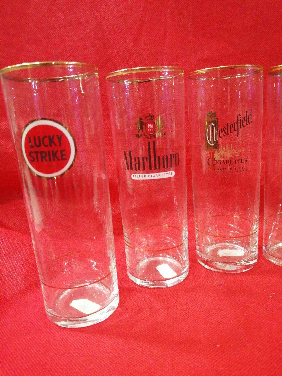 Vasos de tubo con filo dorado y decoración de marcas de cigarrillos como Marlboro y Lucky Strike. Set de 6 piezas para decoración vintage.