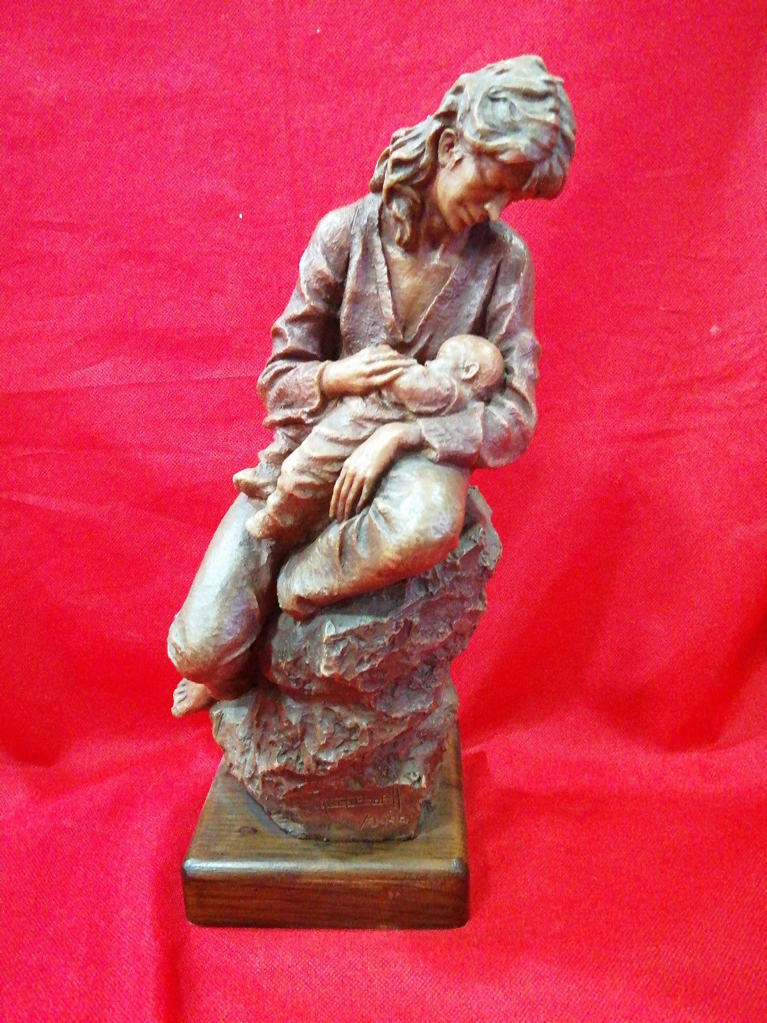 Escultura de maternidad en resina firmada, muestra a madre con bebé en brazos sobre base de madera. Decoración de alta calidad para el hogar.