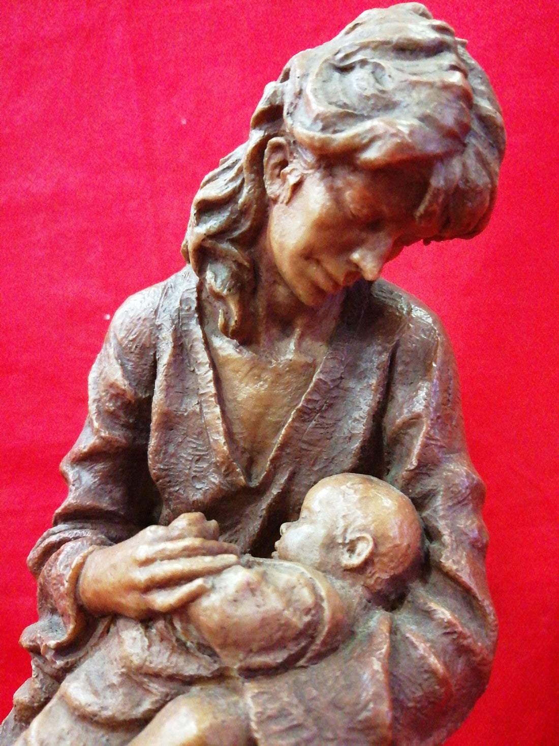 Escultura de maternidad en resina firmada, muestra a madre con bebé en brazos sobre base de madera. Decoración de alta calidad para el hogar.