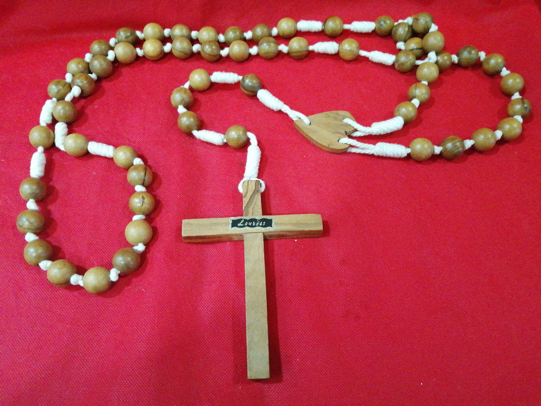 Rosario antiguo de madera con cuentas grandes y cruz tallada, ideal para decoración y oración. Diseño clásico sobre fondo rojo.