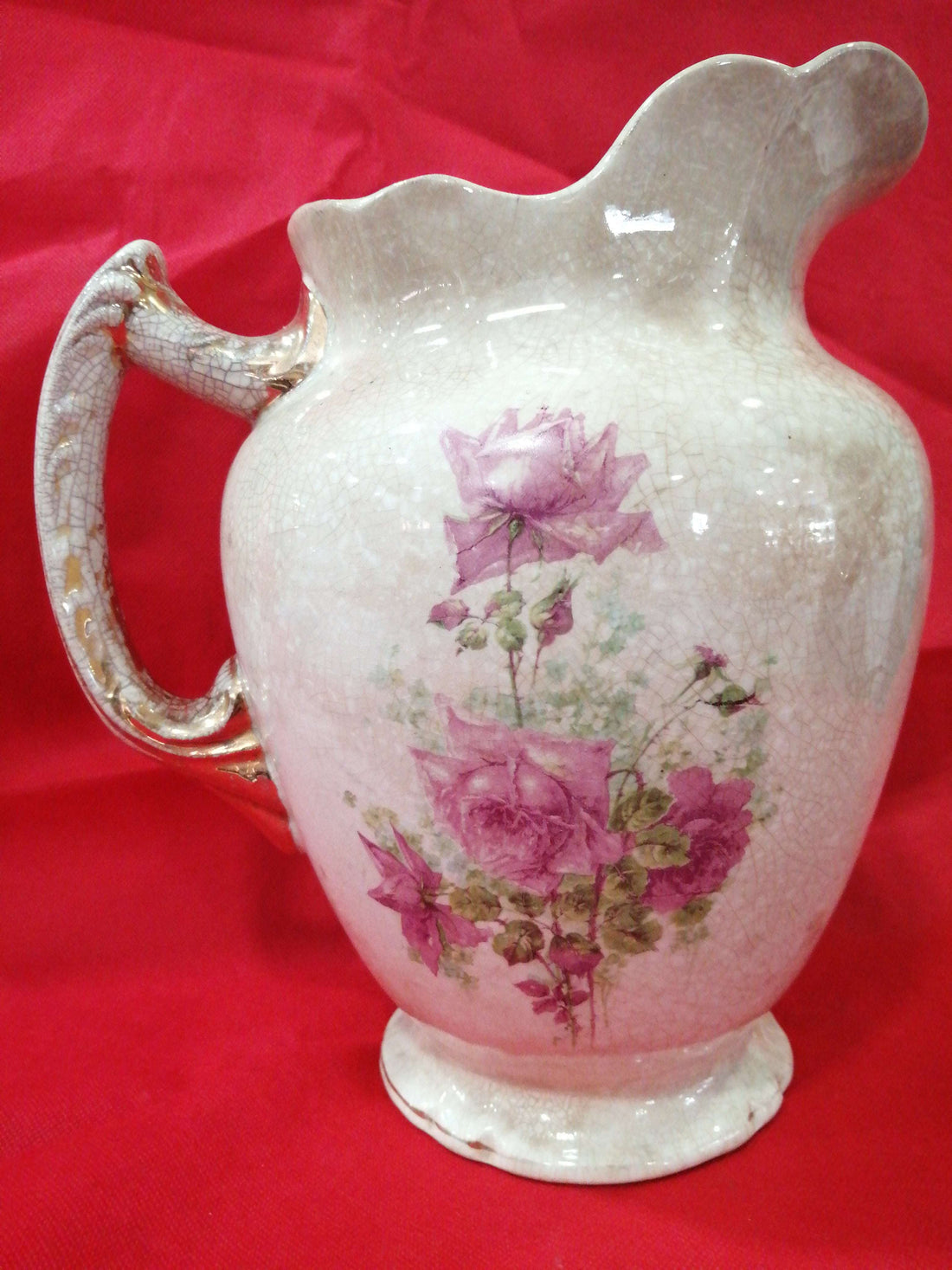 Jarra antigua de palanganero pintada a mano con diseño floral en tonos rosados sobre porcelana craquelada. Ideal para decoración vintage en el hogar.