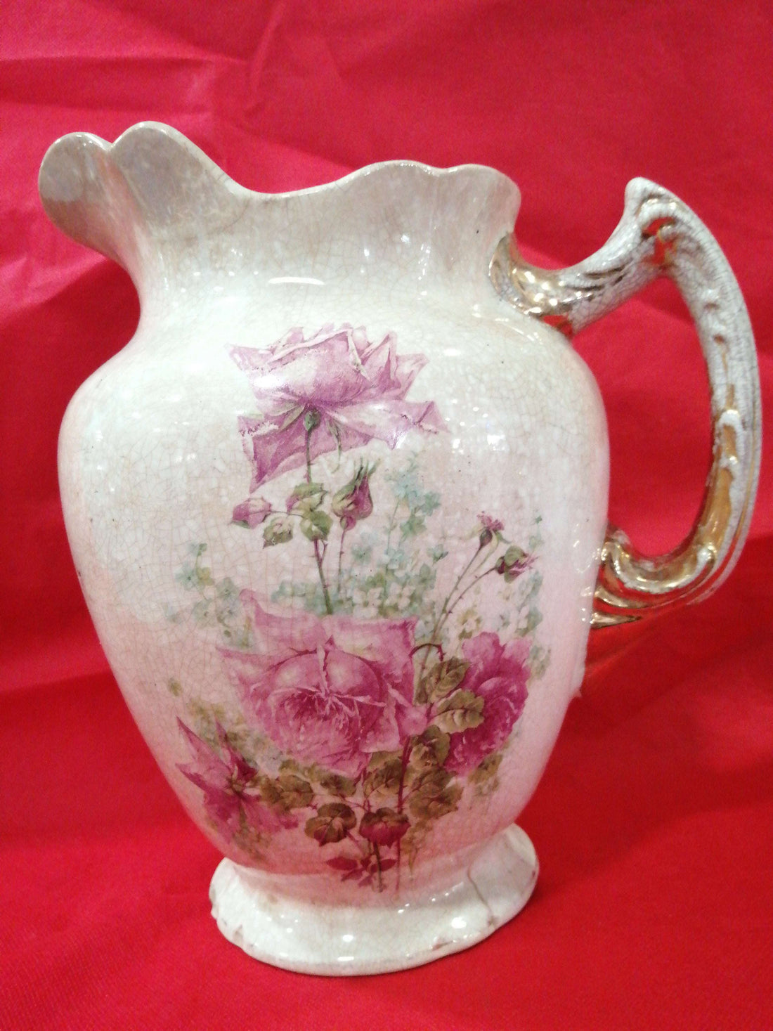 Jarra antigua de palanganero pintada a mano con diseño floral en tonos rosados sobre porcelana craquelada. Ideal para decoración vintage en el hogar.