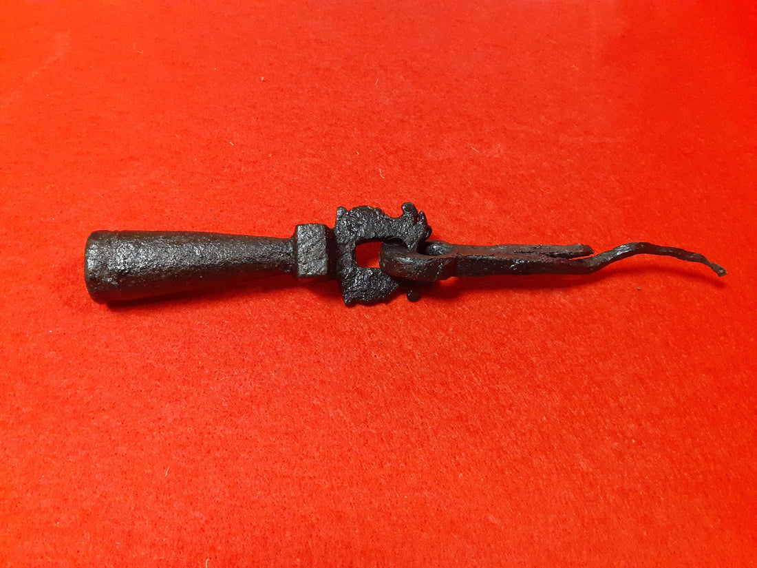 Aldaba-llamador de puerta antiguo S. XVIII en hierro forjado con diseño ornamental sobre fondo rojo, ideal para decoración vintage en el hogar.