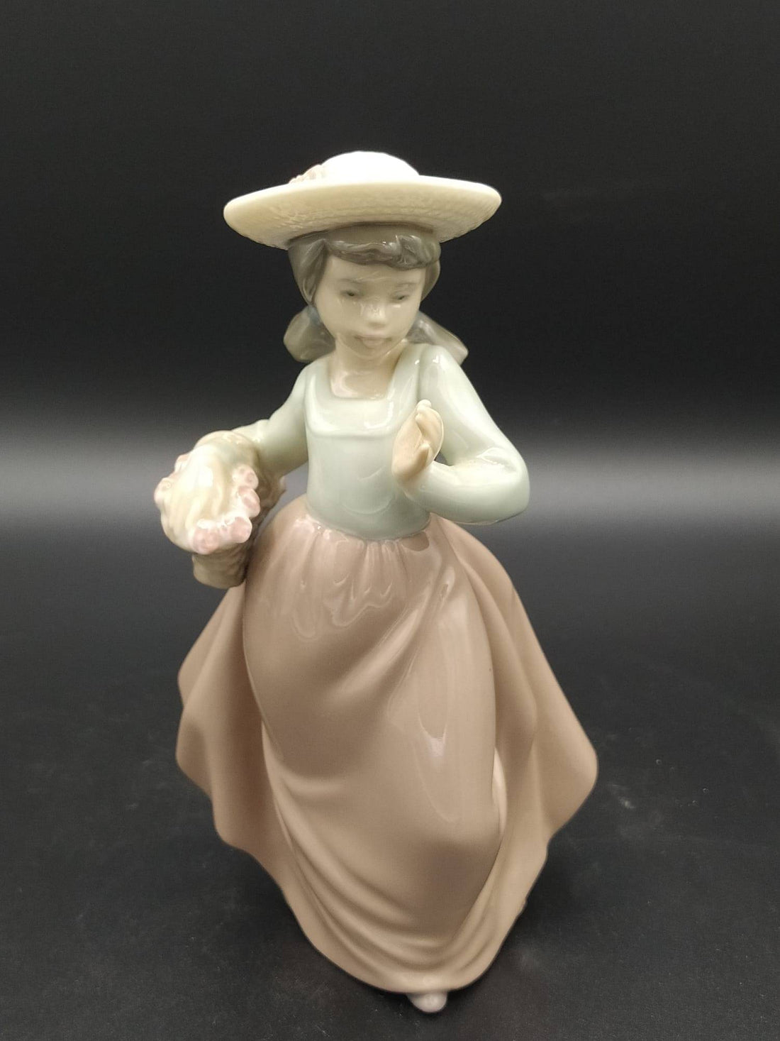 Figura de porcelana Nao Lladó de niña con sombrero y cesta de flores, ideal para decoración de interiores y coleccionistas de arte.