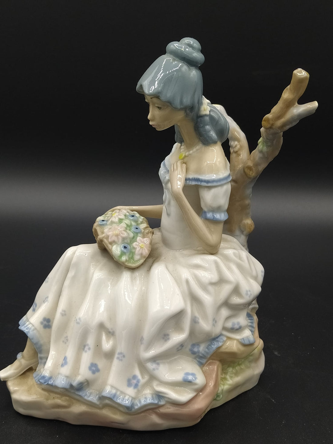 Figura de porcelana Mujer con Flores de Casades sentada con vestido blanco y detalles florales, ideal para decoración elegante de interiores.