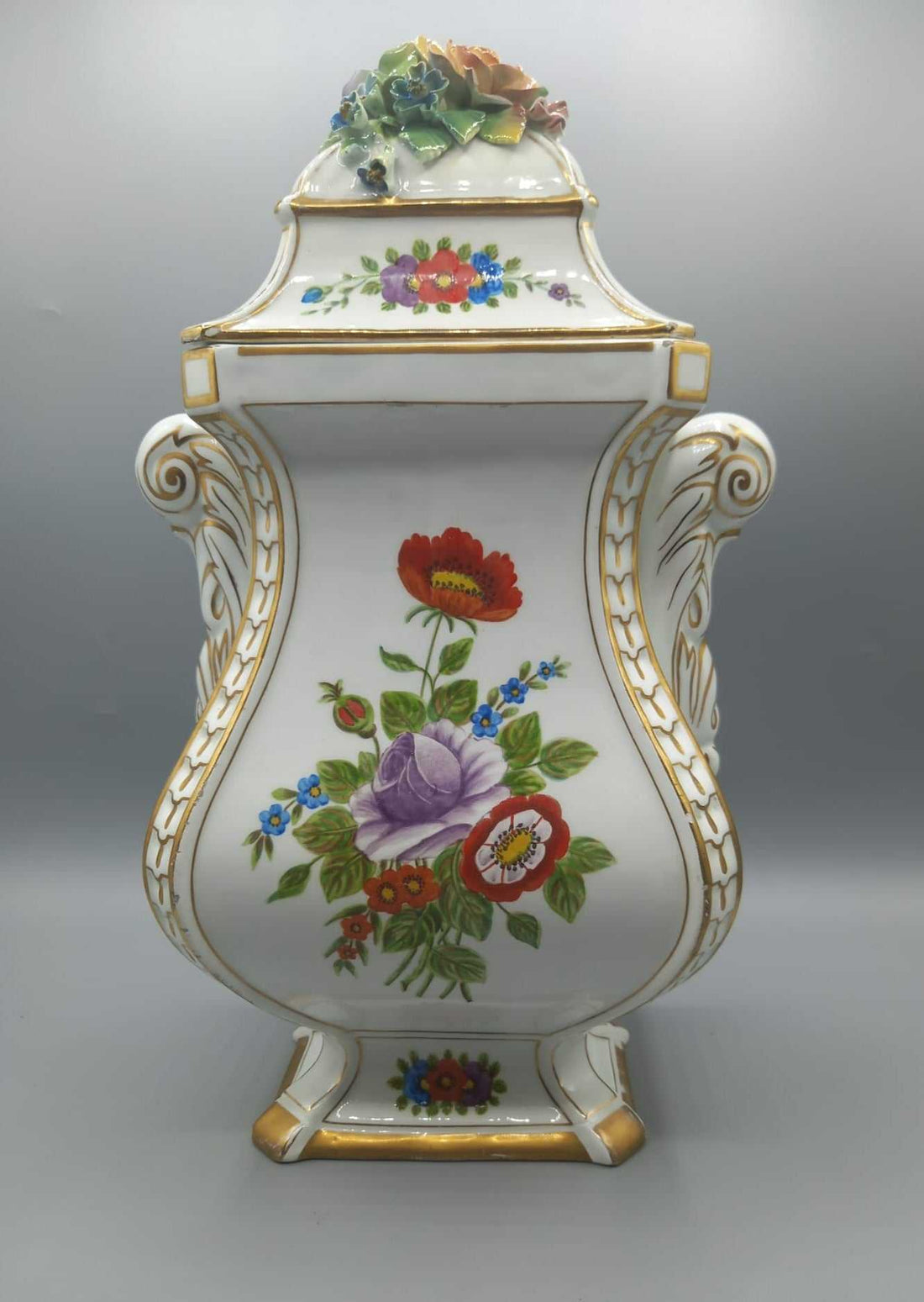 Jarrón de porcelana pintado con detalle floral, calidad superior, con tapa decorada y bordes dorados, ideal para decoración de interiores.