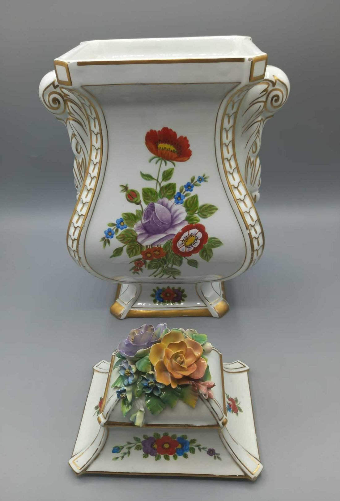 Jarrón de porcelana pintado con detalle floral, calidad superior, con tapa decorada y bordes dorados, ideal para decoración de interiores.