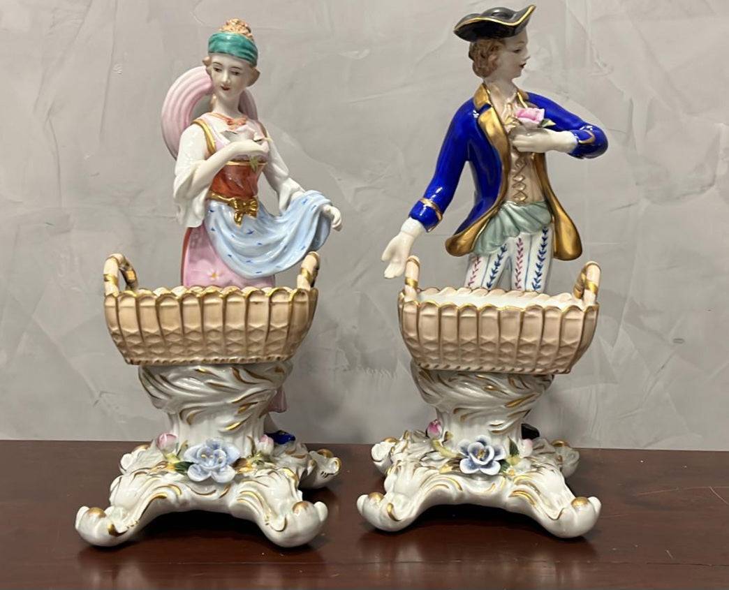 Figuras de porcelana Sèvres hombre y mujer recreación siglo XVIII con canastas decorativas sobre base floral, ideales para decoración clásica.