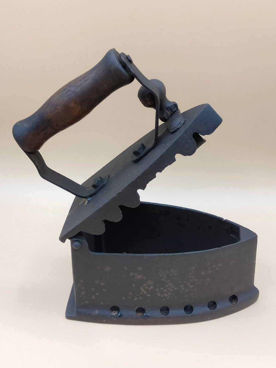 Plancha de carbón fundición antigua con tapa abierta y mango de madera, ideal para decoración vintage en hogar o colección de antigüedades.