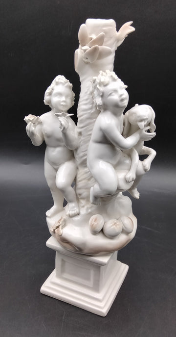 Figura Niños Jugando con Perro - Figura | Porcelana Alemana con dos niños y un perro junto a un tronco decorativo, ideal para decoración de interiores.