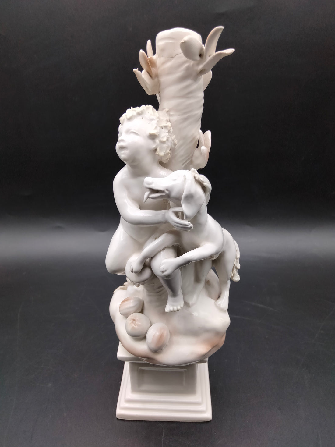 Figura Niños Jugando con Perro - Figura | Porcelana Alemana con dos niños y un perro junto a un tronco decorativo, ideal para decoración de interiores.