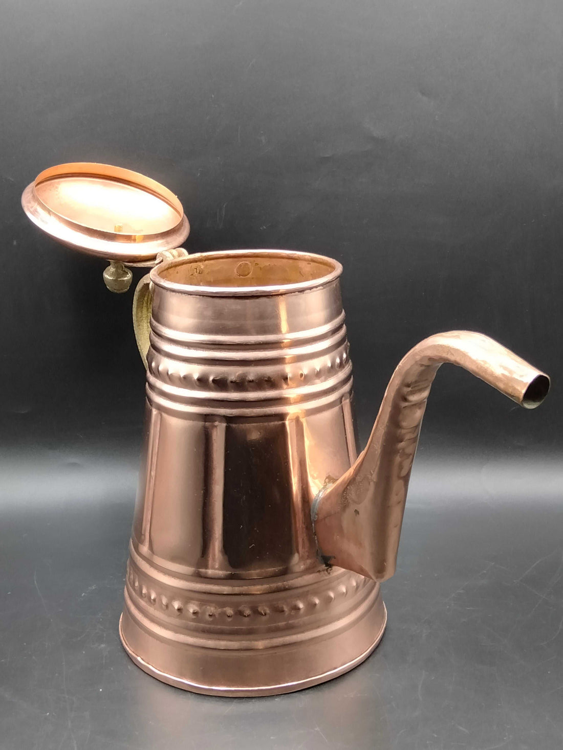 Cafetera de cobre con mango metálico, decorada con relieves artesanales, ideal para decoración vintage en cocina o sala de estar.