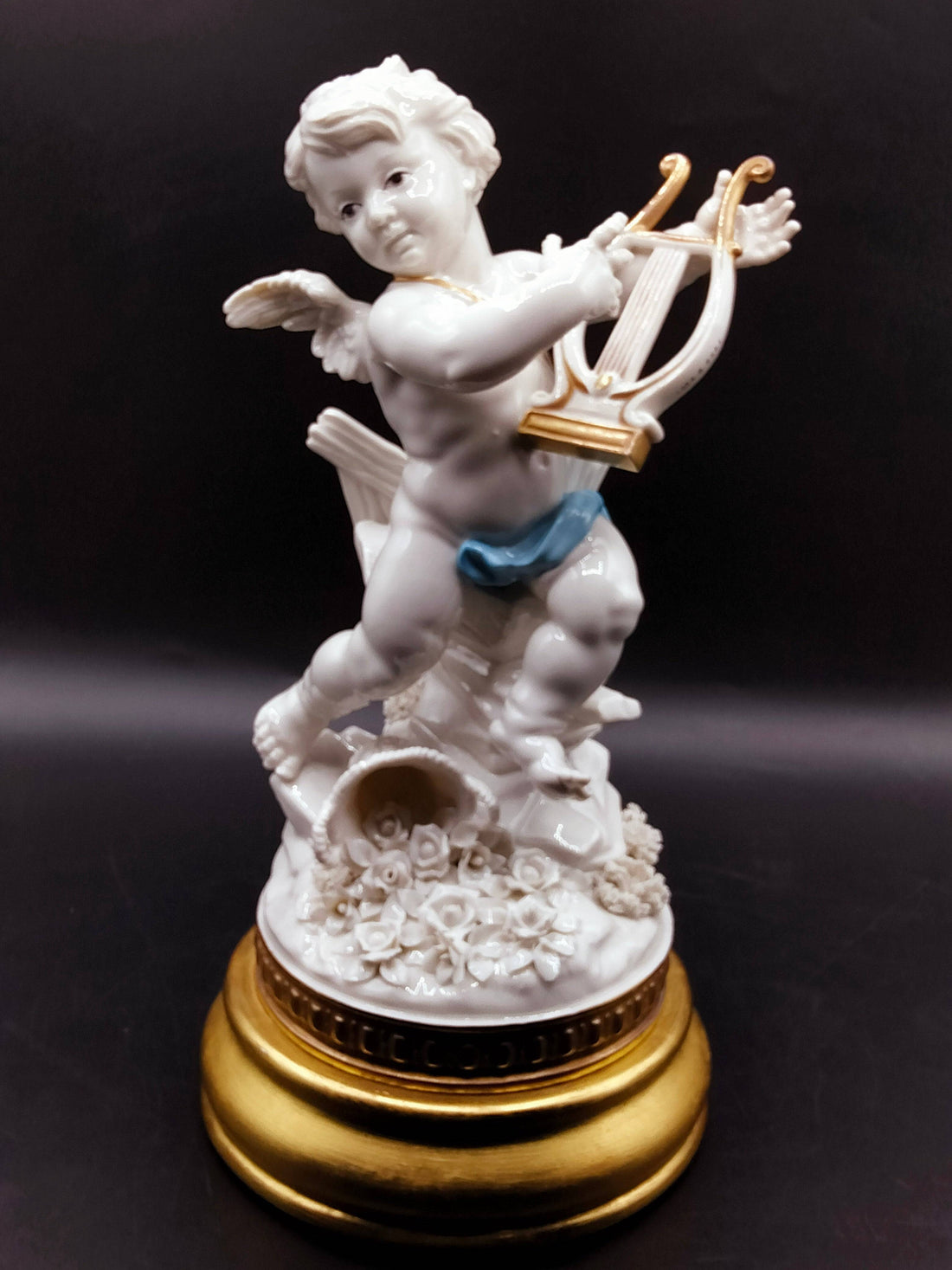 Figura de porcelana Angél Algora con arpa sobre base dorada, ideal para decoración de interiores con estilo clásico y simbolismo de prosperidad.