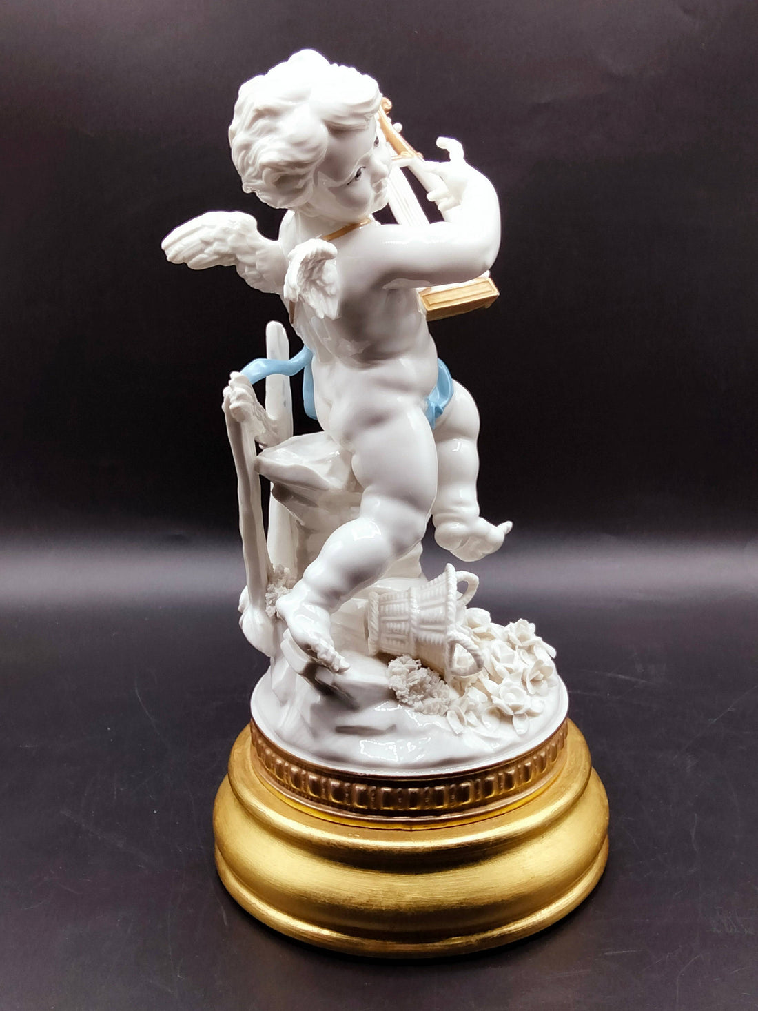 Figura de porcelana Angél Algora con arpa sobre base dorada, ideal para decoración de interiores con estilo clásico y simbolismo de prosperidad.