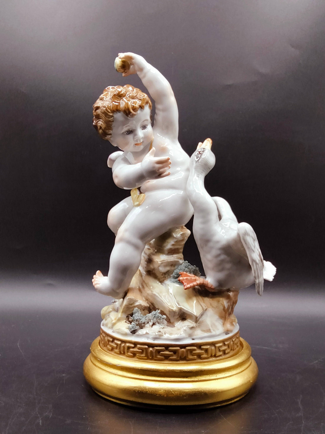 Figura Ángel con Pato - Elegancia y Lujo | Decoración en porcelana fina, muestra un ángel alado interactuando con un pato sobre base dorada.