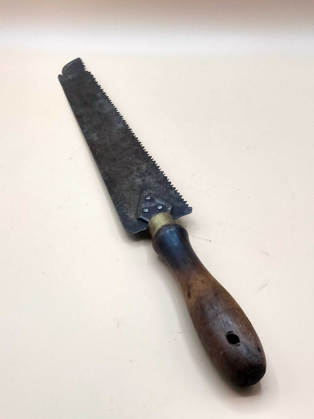 Sierra de mano antigua para carpintería con mango de madera oscura y hoja metálica dentada, ideal para decoración vintage en hogar y jardín.