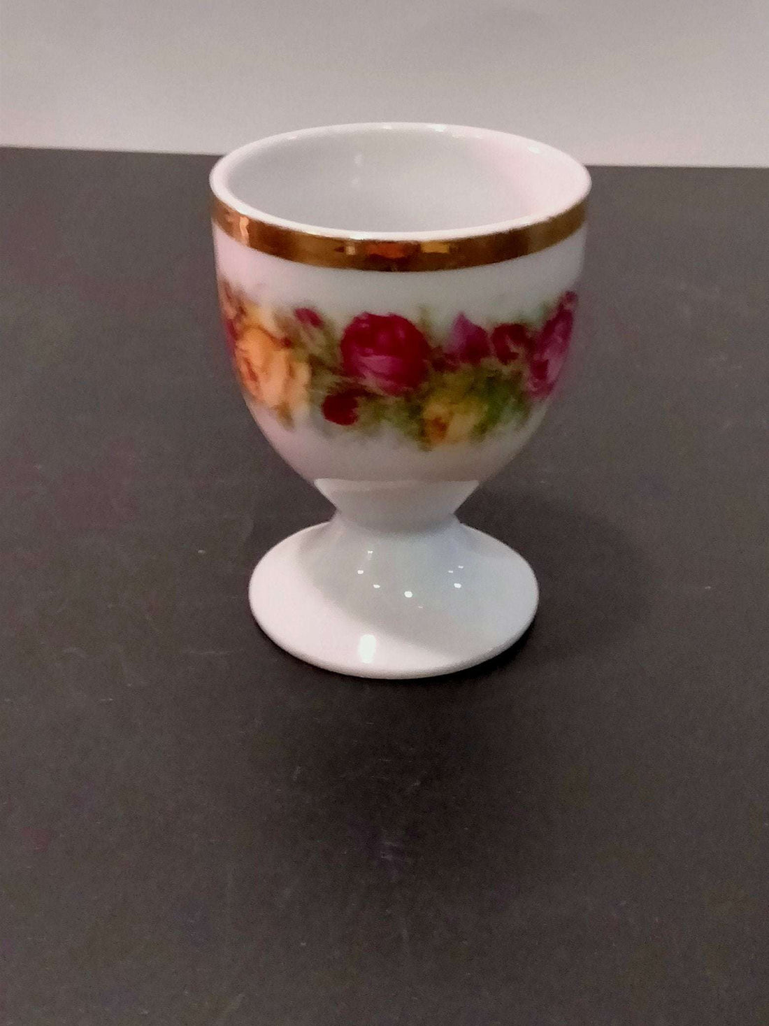 Juego de 4 hueveros de porcelana decorados con motivos frutales en tonos rojos y amarillos, ideal para decoración vintage de cocina.