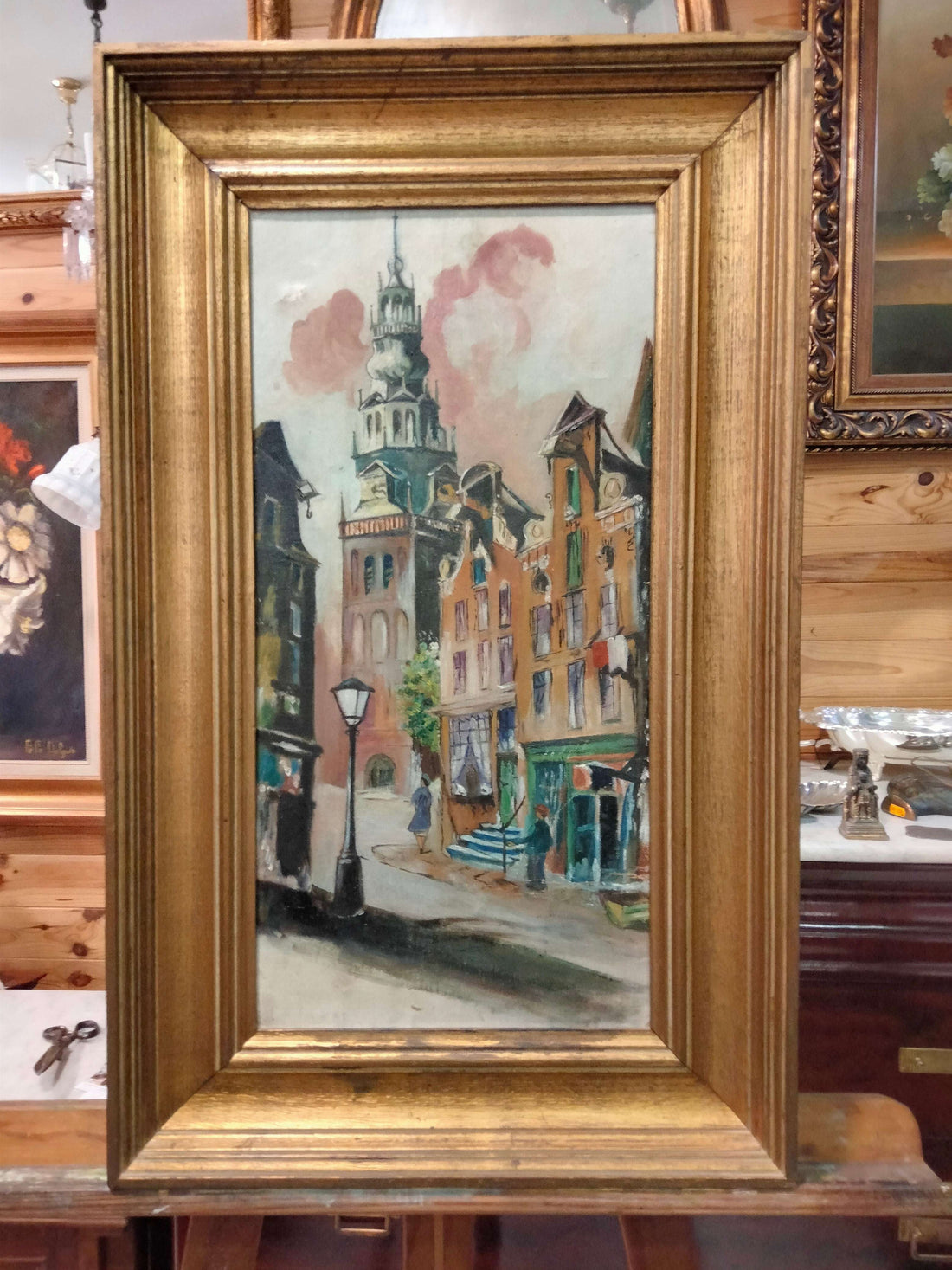 Óleo paisajístico urbano con detalles arquitectónicos clásicos, enmarcado en madera dorada. Ideal para decoración de interiores elegantes.