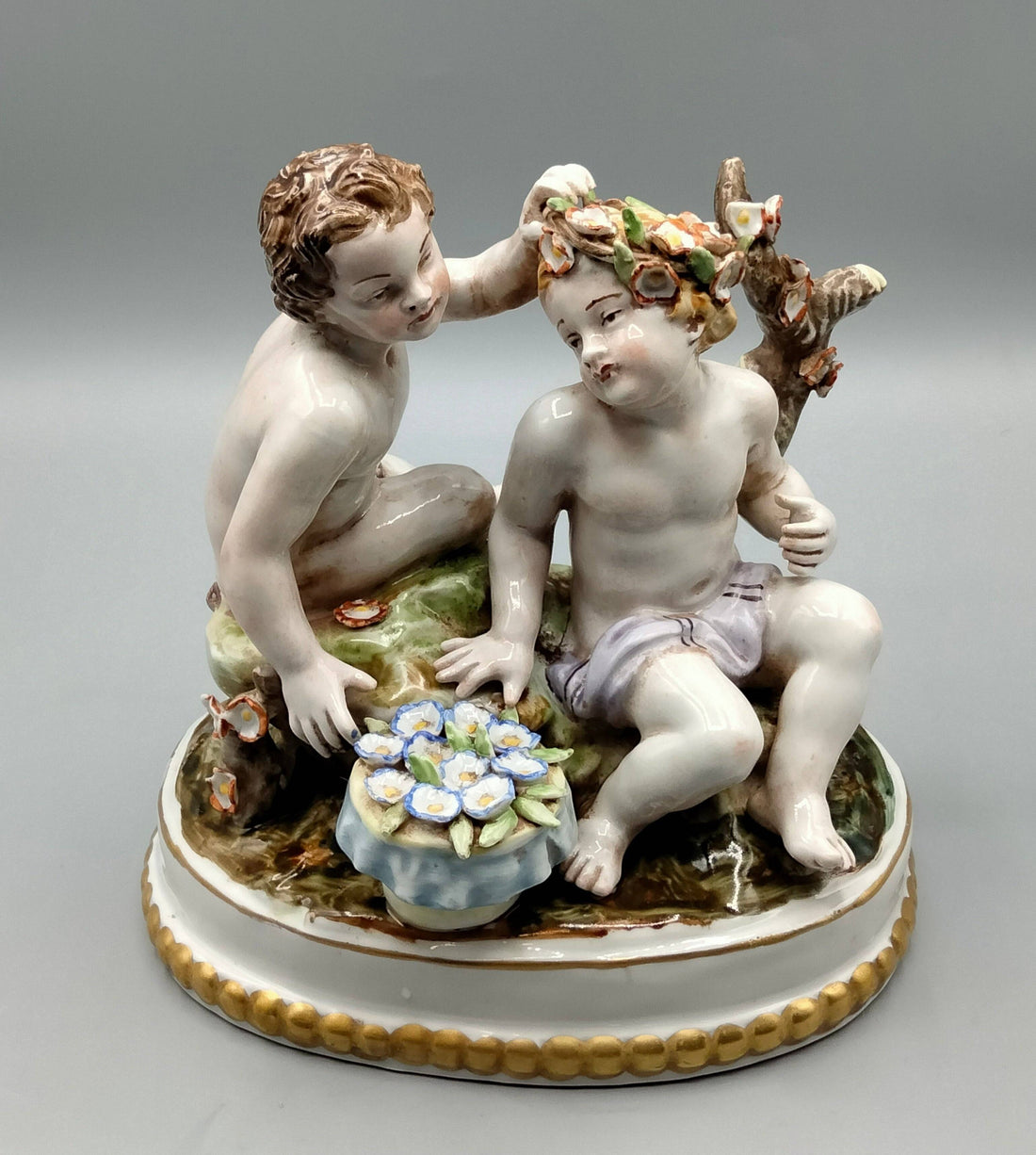 Figura de porcelana Hispania Manises con niños jugando con flores, diseño detallado y colores suaves, ideal para decoración clásica.