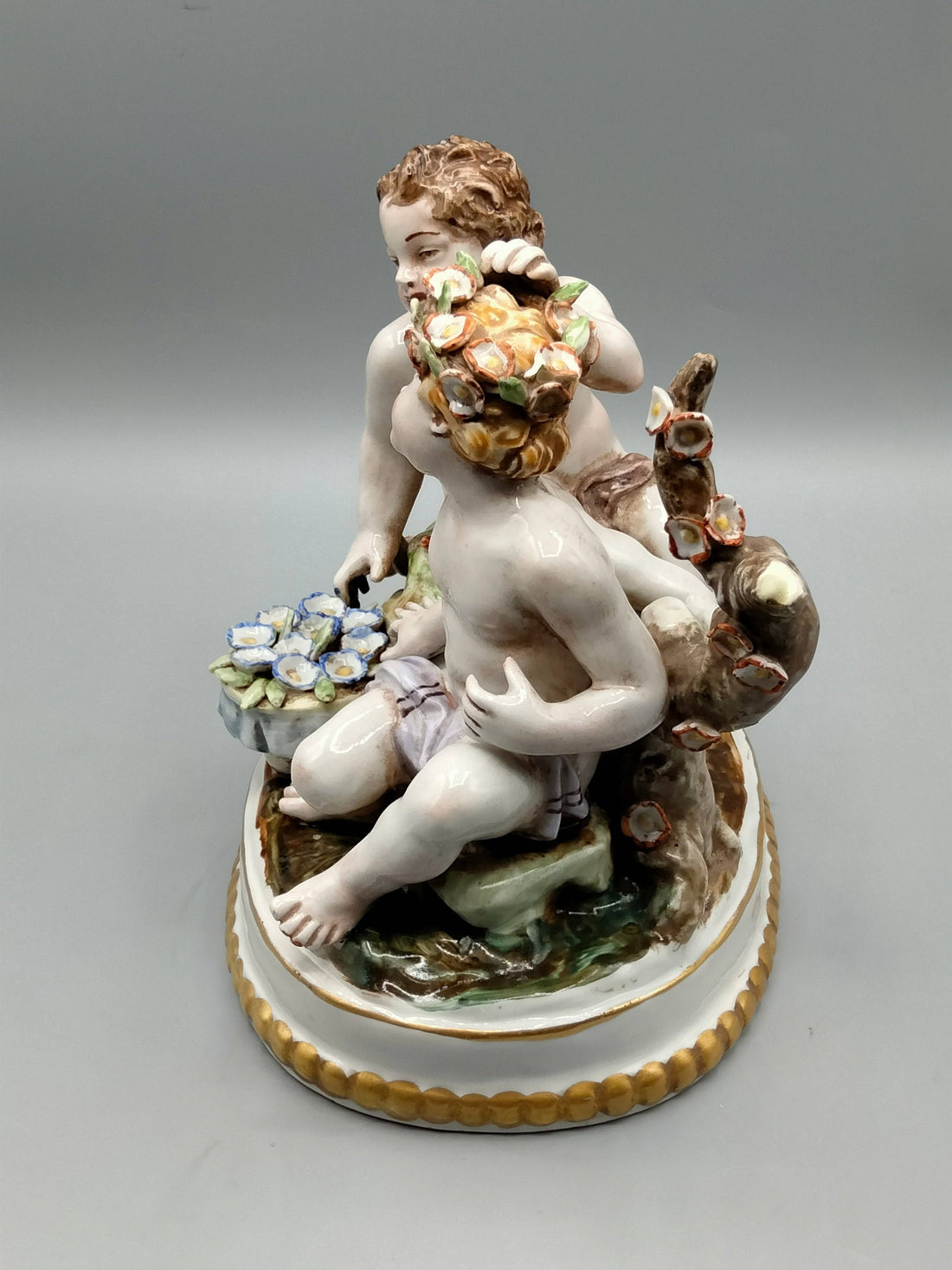 Figura de porcelana Hispania Manises con niños jugando con flores, diseño detallado y colores suaves, ideal para decoración clásica.