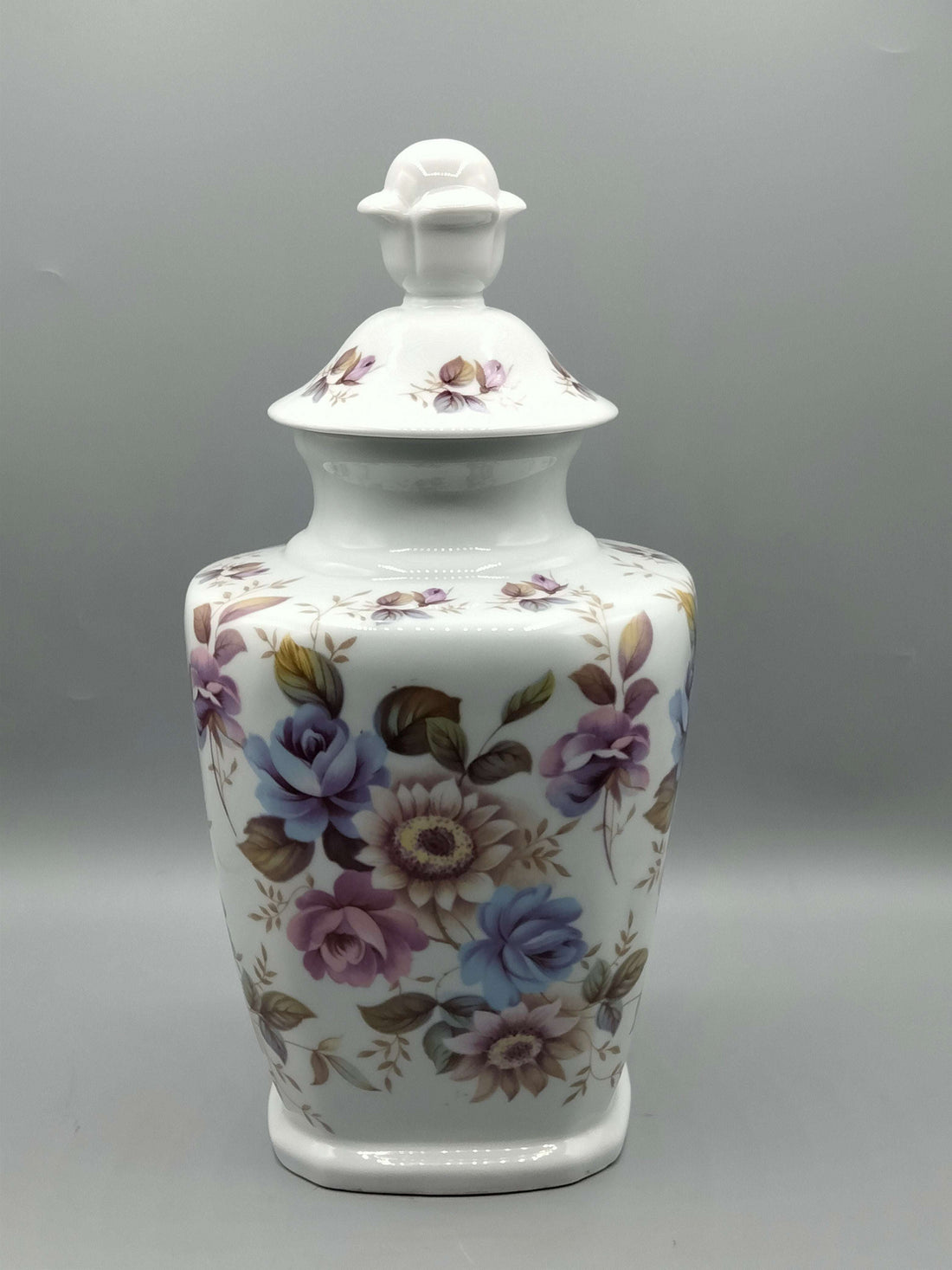 Tibor de porcelana decorado con flores en tonos lilas y azules, ideal para decoración floral en interiores. Calidad y elegancia para el hogar.