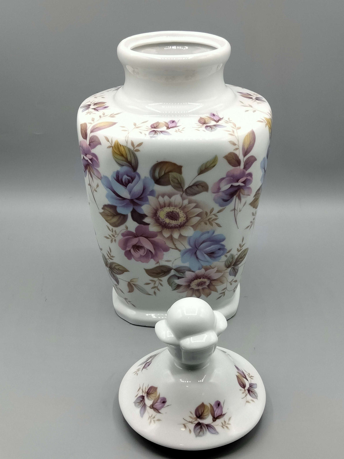 Tibor de porcelana decorado con flores en tonos lilas y azules, ideal para decoración floral en interiores. Calidad y elegancia para el hogar.