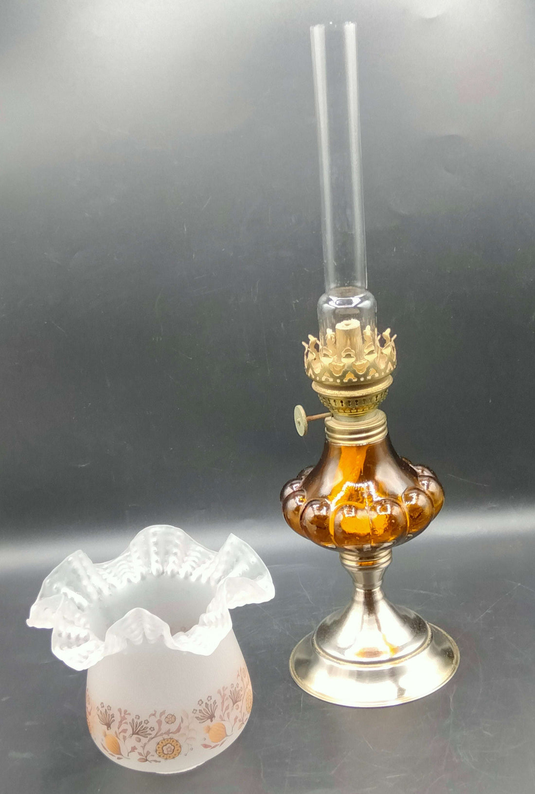 Quinque de cristal ámbar con base metálica y pantalla decorativa floral, estilo años 60, decoración ideal para tu hogar vintage.