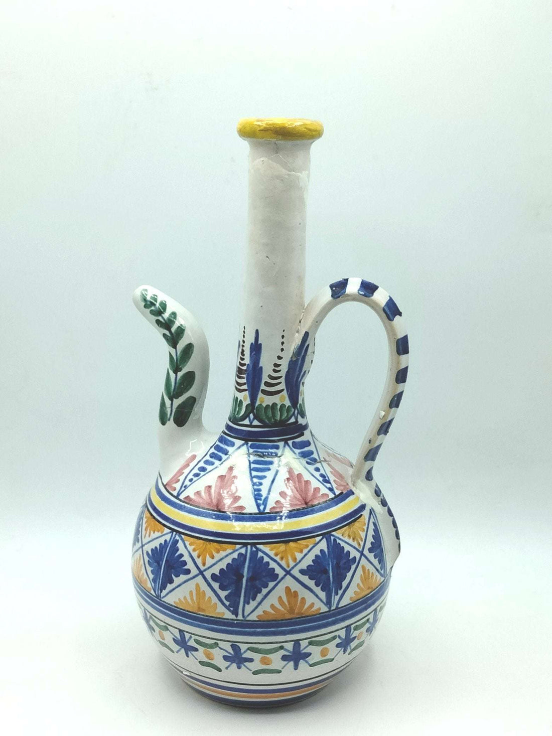 Botijo artesanal de cerámica pintado a mano con motivos florales y geométricos en azul, amarillo y verde. Bucaro decorativo único para hogar.