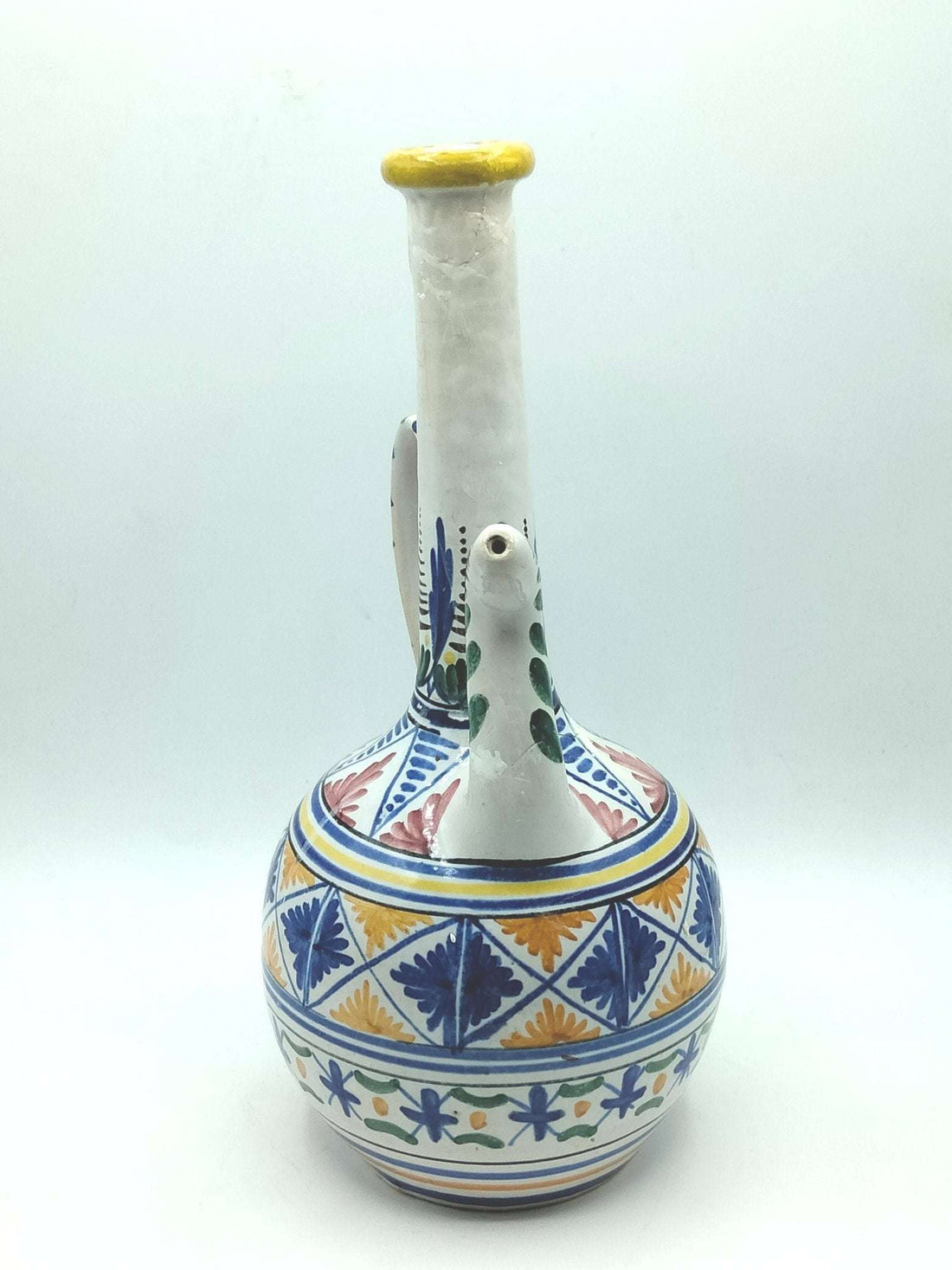 Botijo artesanal de cerámica pintado a mano con motivos florales y geométricos en azul, amarillo y verde. Bucaro decorativo único para hogar.