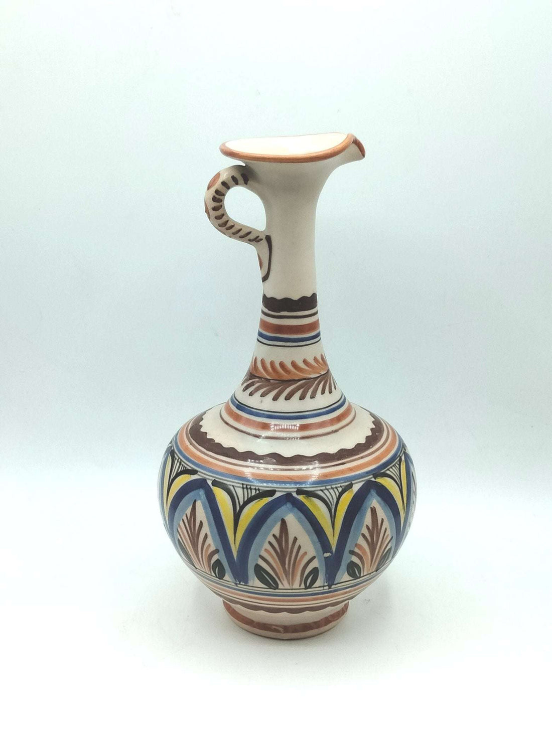 Jarra ceramica artesanal con diseño elegante pintado a mano en tonos tierra, azul y amarillo. Ideal para decoración de interiores estilo rústico.