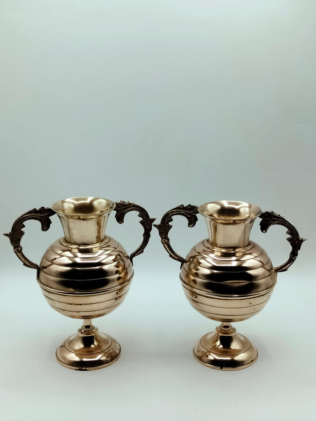 Ánforas de bronce con detalles elegantes y asas ornamentadas, ideales para decoración clásica en el hogar. Producto exclusivo de Cositas Antiguas.