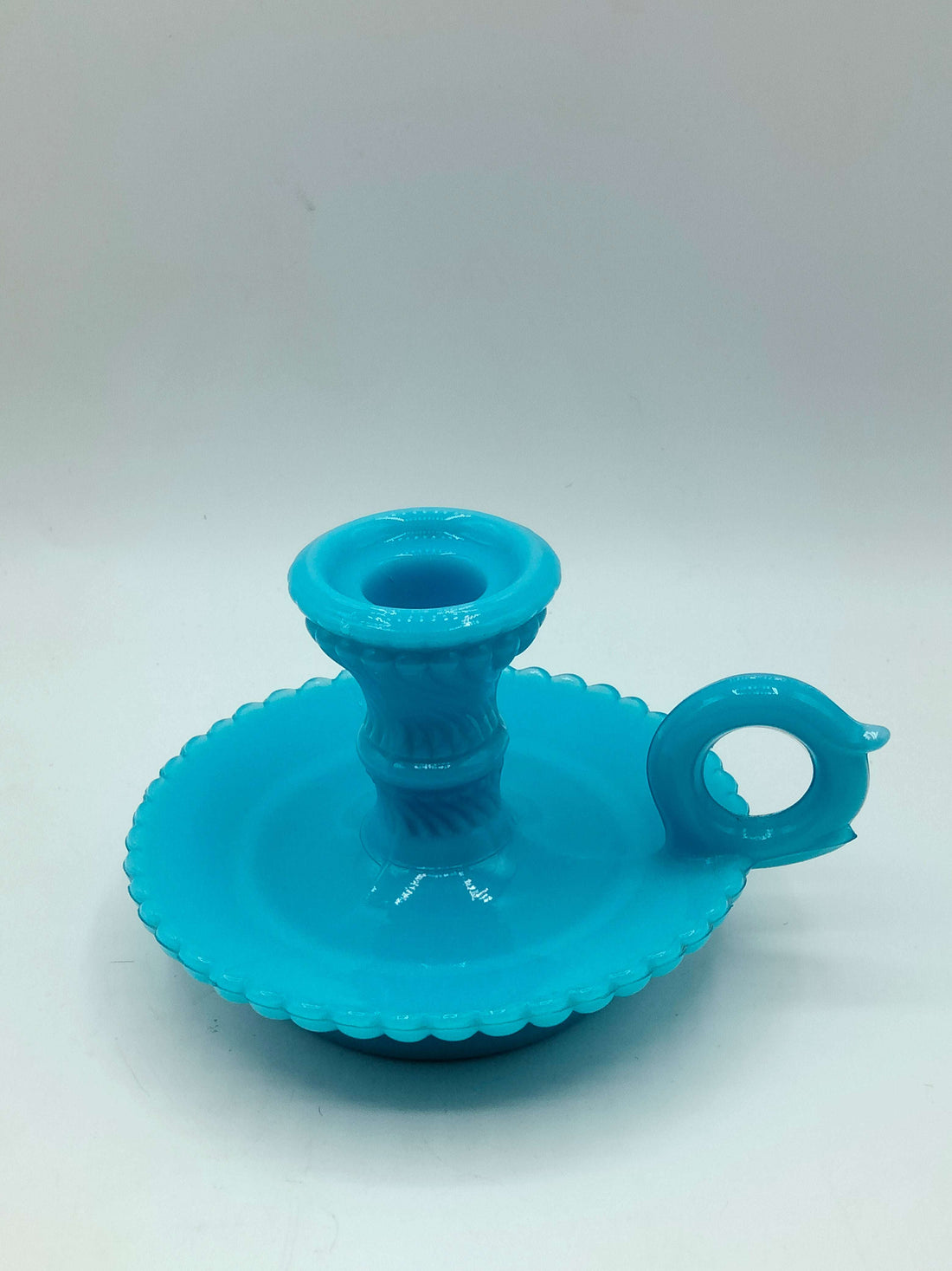 Palmatoria de opalina azul elegante con borde ondulado y mango circular, vista frontal