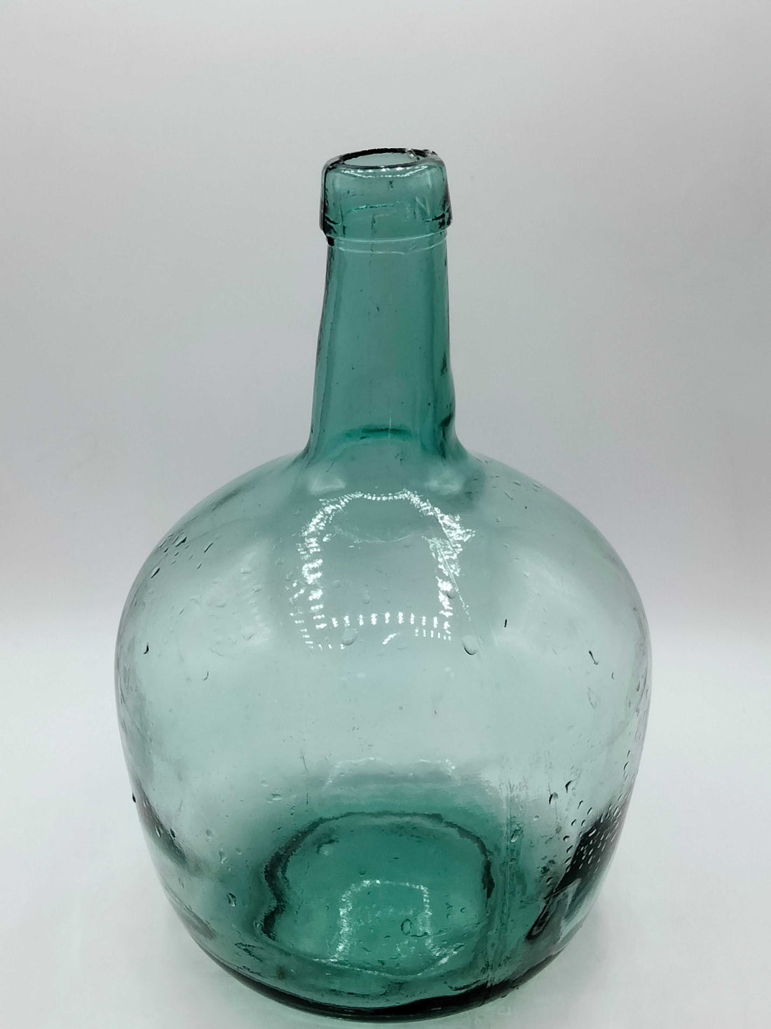 Damajuana 5 litros de cristal soplado verde con acabado artesanal, ideal para decoración vintage en interiores de hogar o jardín.