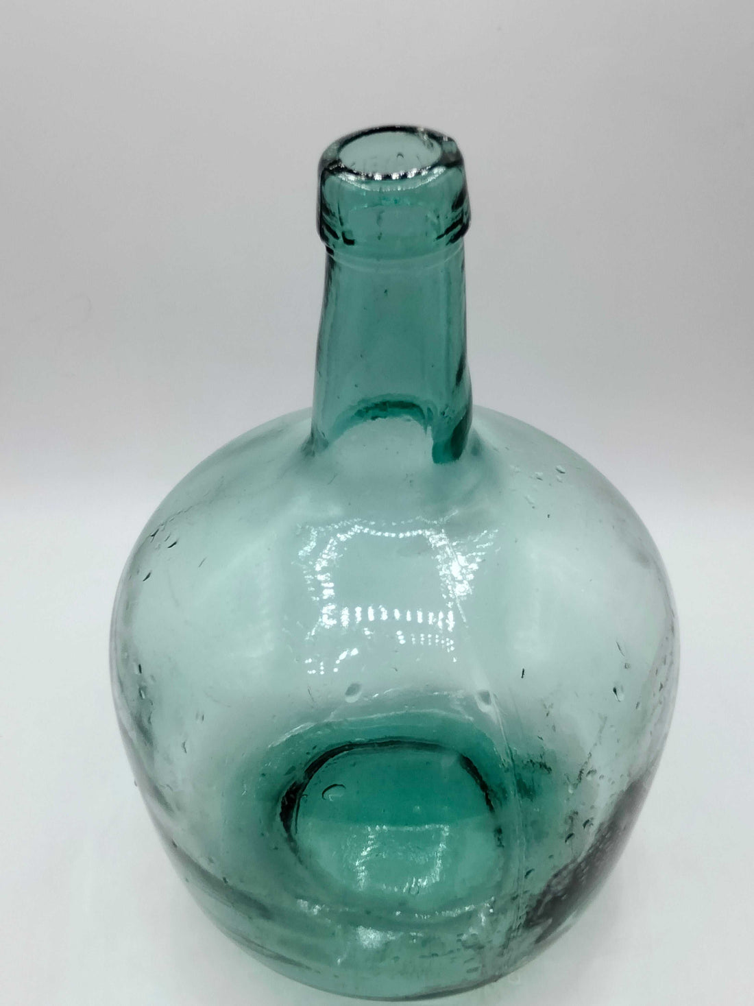 Damajuana 5 litros de cristal soplado verde con acabado artesanal, ideal para decoración vintage en interiores de hogar o jardín.