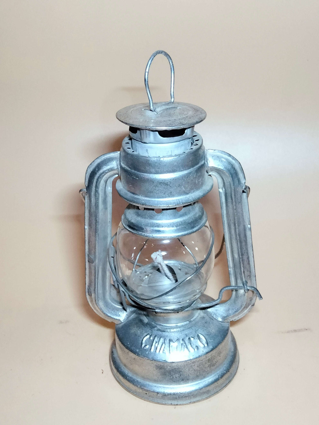 Lámpara de petróleo Chamaco con diseño nostálgico en metal plateado, ideal para decoración vintage en interiores o exteriores del hogar.