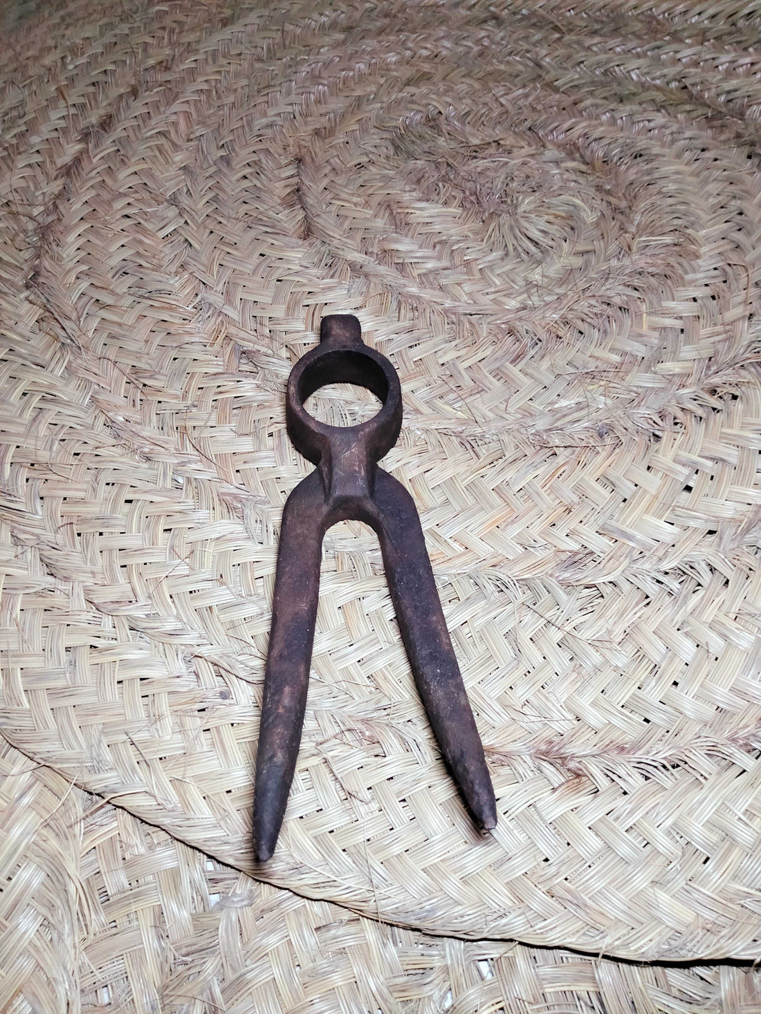 Pico antiguo para remolacha de hierro oxidado sobre esterilla de esparto, ideal como decoración rústica en hogar o jardín. Herramienta de campo histórica.