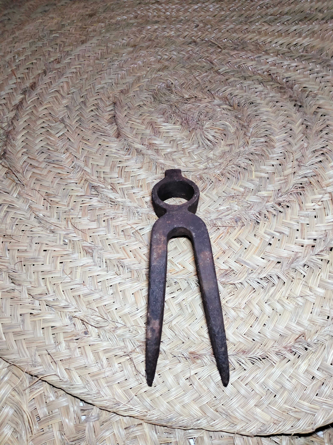 Pico antiguo para remolacha de hierro oxidado sobre esterilla de esparto, ideal como decoración rústica en hogar o jardín. Herramienta de campo histórica.