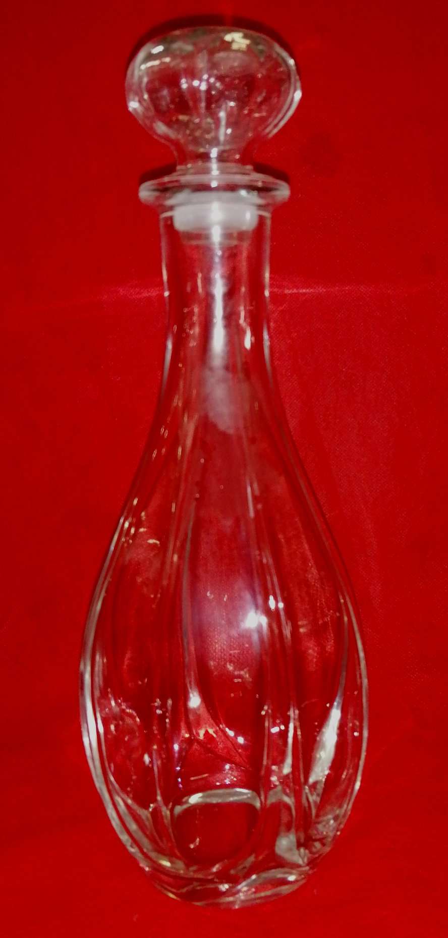 Botella licorera de cristal con diseño elegante y tapón redondo, ideal para decoración y almacenamiento de licores en el hogar.