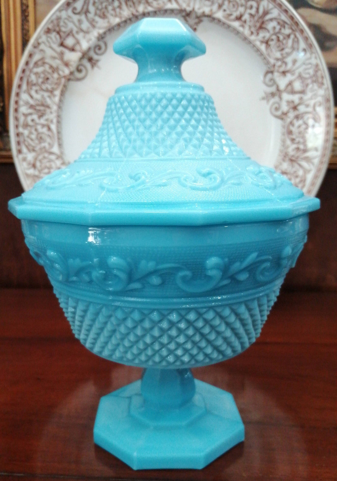 Bombonera Opalina azul con tapa decorada y diseño tipo copa sobre base hexagonal. Ideal para decoración elegante en hogar o jardín.