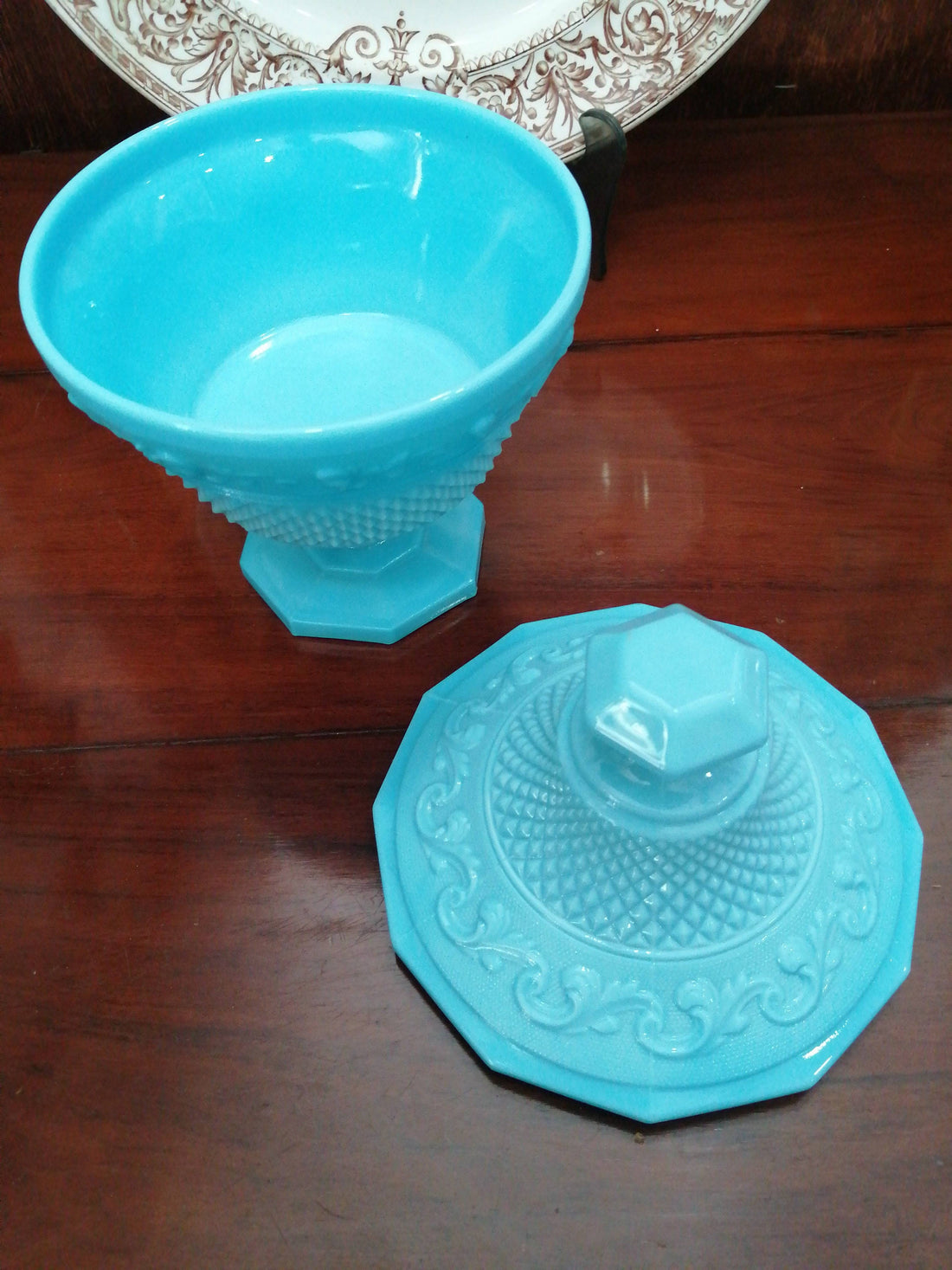 Bombonera Opalina azul con tapa decorada y diseño tipo copa sobre base hexagonal. Ideal para decoración elegante en hogar o jardín.