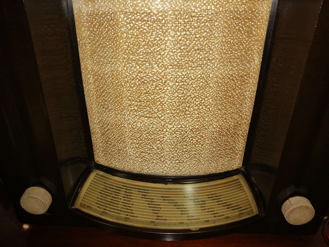 Radio de válvulas tipo teatro con carcasa de madera oscura y rejilla frontal de tela, auténtico estilo vintage para decoración clásica.