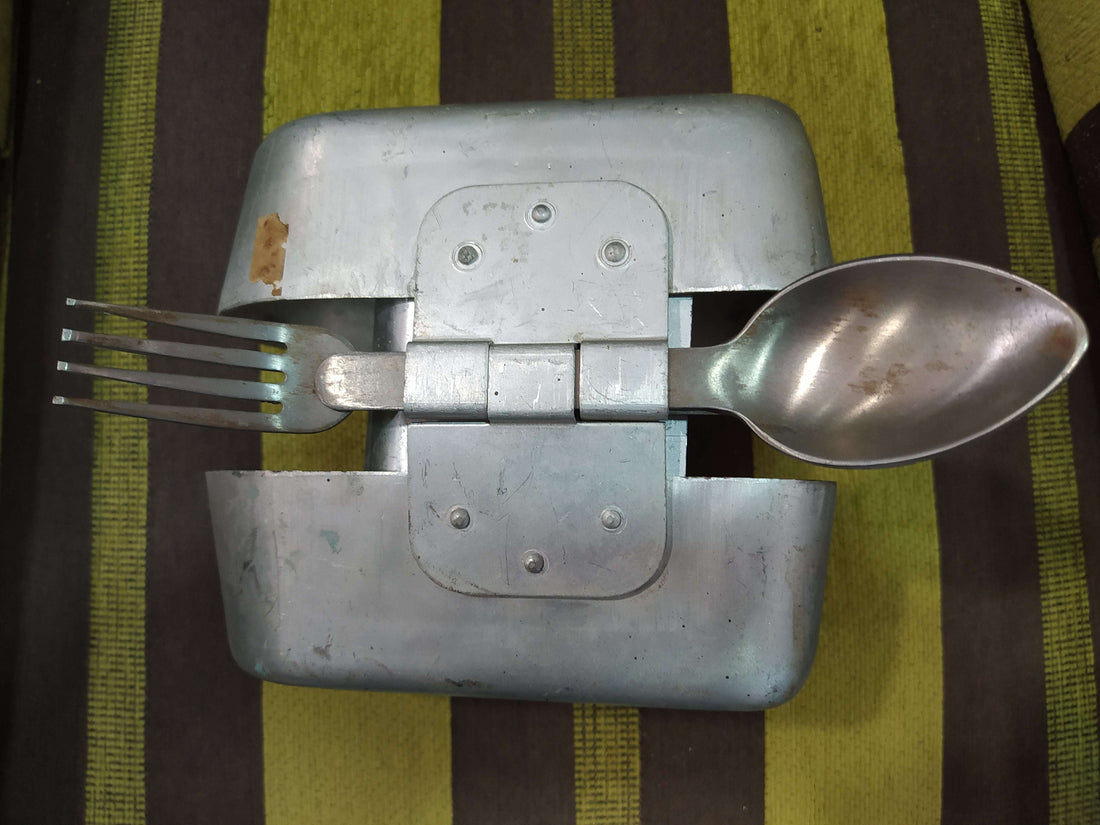 Fiambrera de aluminio antigua militar con cubiertos incluidos, ideal para decoración vintage en hogar o jardín. Incluye cuchara y tenedor metálicos.