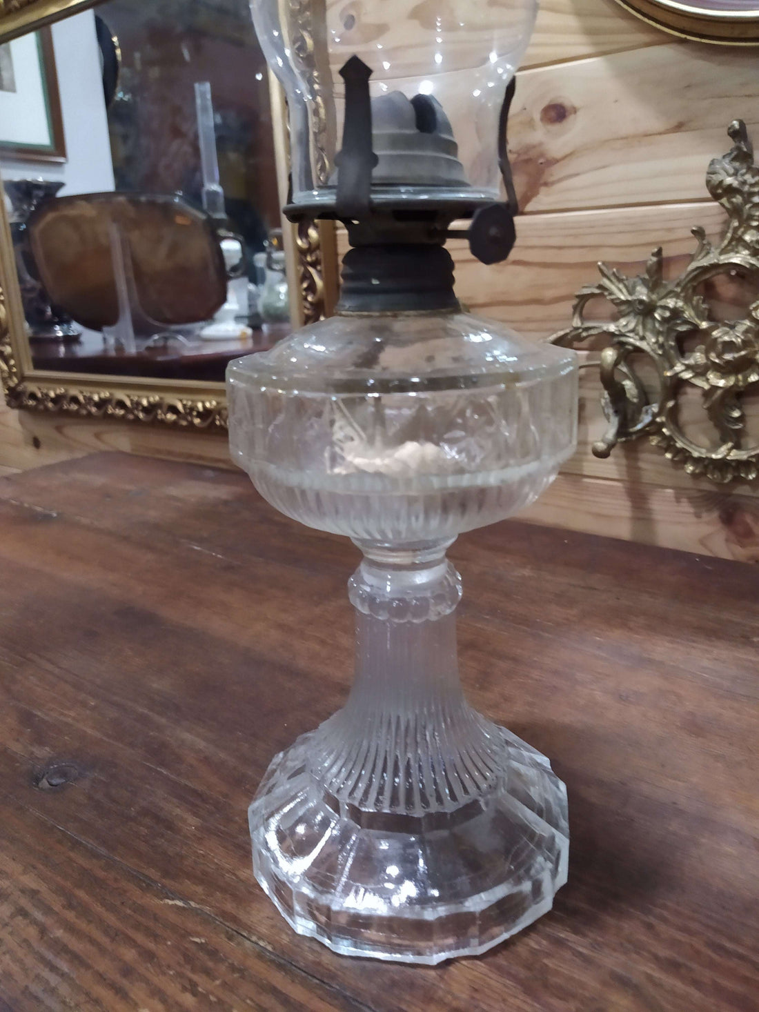 Quinque antiguo de cristal con base tallada y chimenea alta, ideal para decoración vintage en interiores elegantes. Pieza de colección con gran detalle.